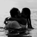 Beach Days - Man and Woman Kissing Together on Body of Water