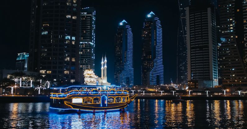 Night Sailing - A Boat Sailing on River Near City Buildings during Night