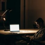 Overnight Stay - Man in Black and White Stripe Dress Shirt Sitting on Chair in Front of Macbook
