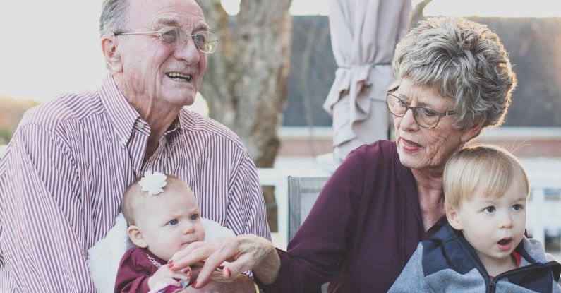 Seniors - Grandmother and Grandfather Holding Child on Their Lap