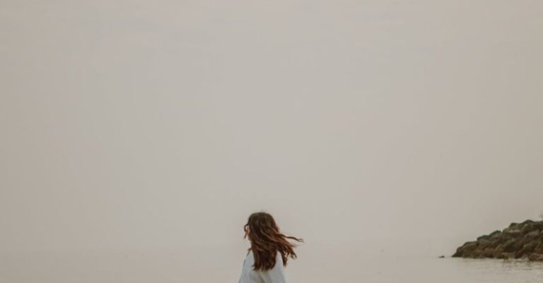 Rough Weather - Anonymous tourist admiring sea from stone in misty weather